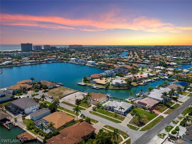 aerial view at dusk featuring a water view