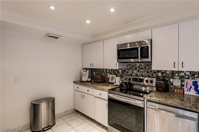 kitchen with white cabinets, tasteful backsplash, appliances with stainless steel finishes, and dark stone counters