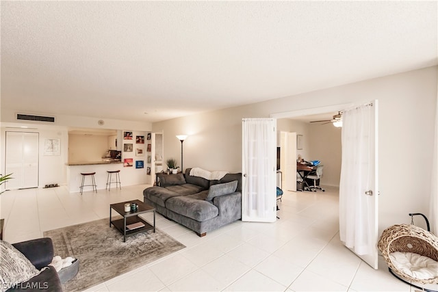 living room featuring a textured ceiling, ceiling fan, and light tile flooring