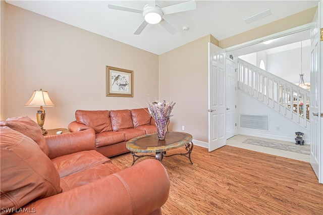 living room featuring ceiling fan with notable chandelier and light hardwood / wood-style flooring