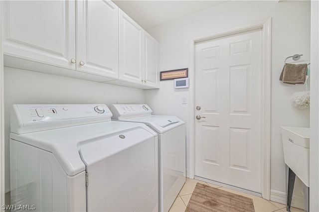 laundry area with light tile flooring, sink, cabinets, and washer and clothes dryer