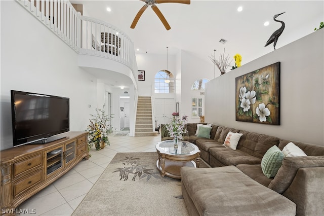 tiled living room with ceiling fan and a towering ceiling