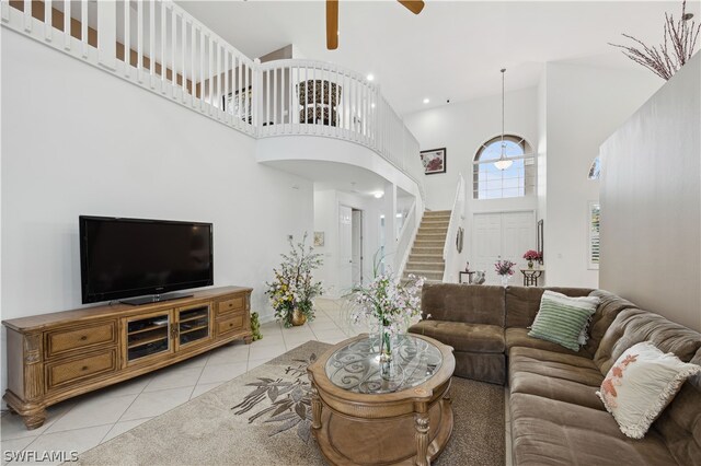 tiled living room featuring ceiling fan and a towering ceiling