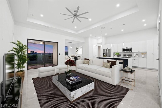 living area featuring a ceiling fan, recessed lighting, a raised ceiling, and a high ceiling