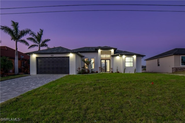 view of front of home with a front yard, decorative driveway, an attached garage, and stucco siding