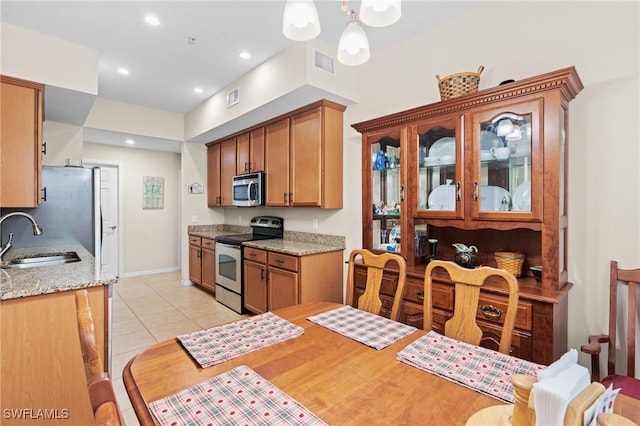 kitchen featuring light stone countertops, stainless steel appliances, sink, pendant lighting, and light tile patterned flooring