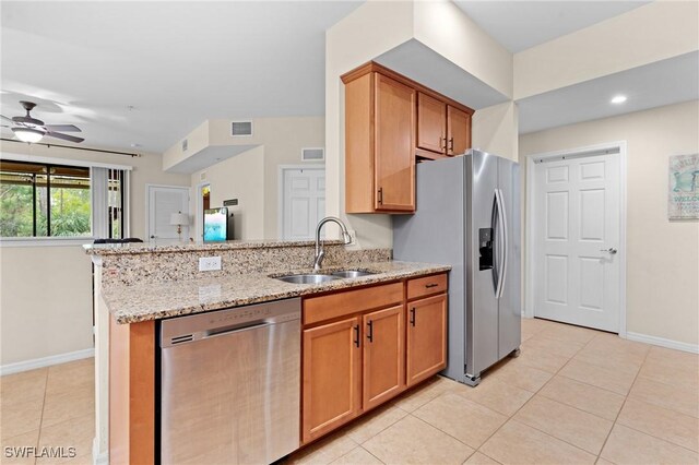 kitchen featuring sink, ceiling fan, light tile patterned floors, light stone countertops, and appliances with stainless steel finishes