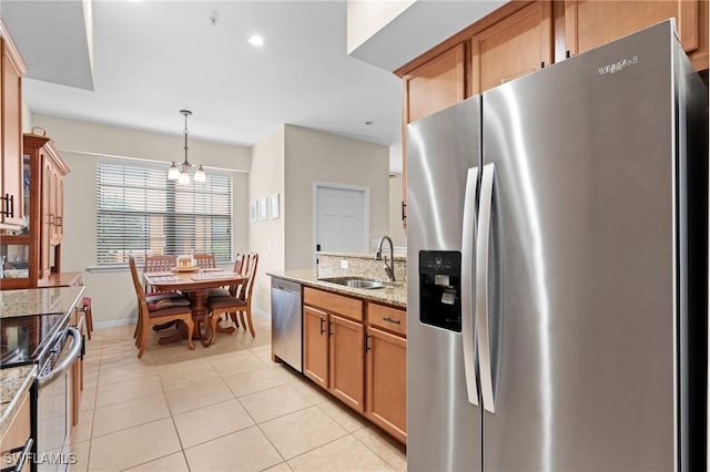 kitchen with sink, light stone counters, a chandelier, decorative light fixtures, and appliances with stainless steel finishes