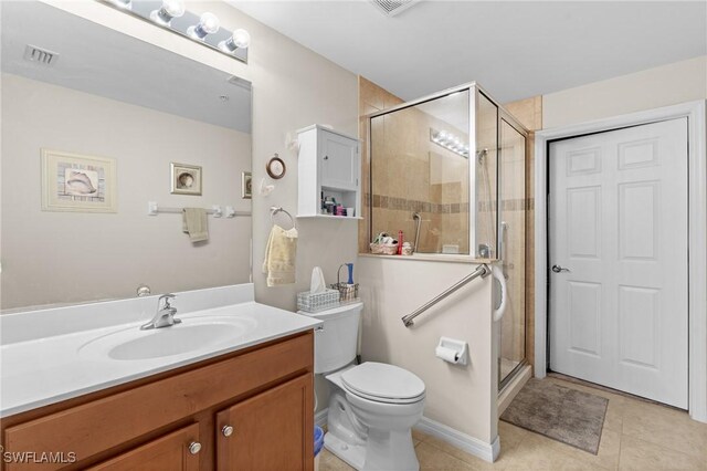 bathroom featuring tile patterned flooring, a shower with door, vanity, and toilet