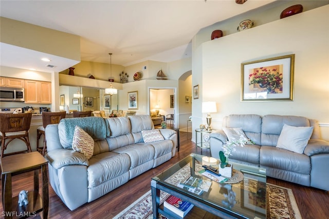 living room with a high ceiling and dark wood-type flooring