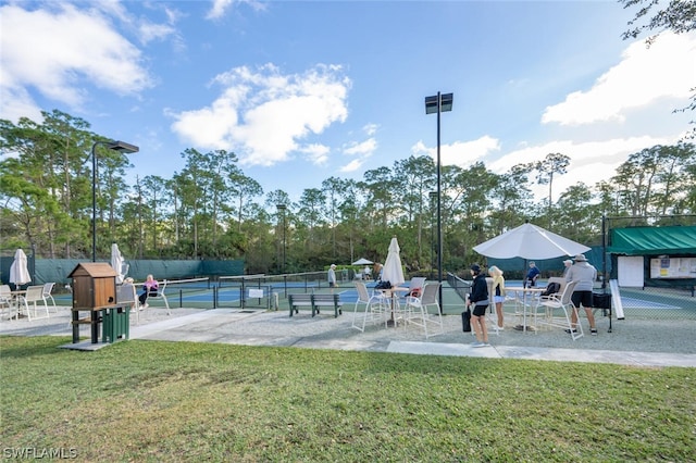 view of home's community with a lawn and tennis court