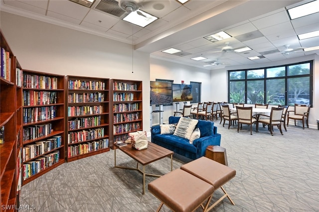 living area featuring light colored carpet, a drop ceiling, and crown molding