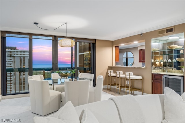 tiled dining area with crown molding, a water view, beverage cooler, and sink