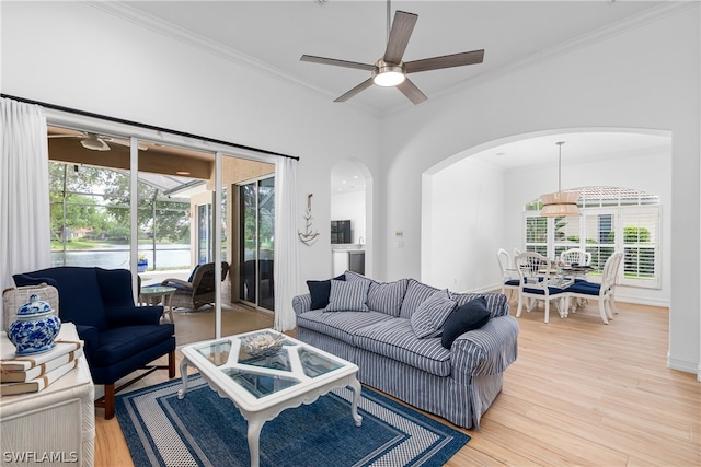 living room with crown molding, ceiling fan, and light wood-type flooring