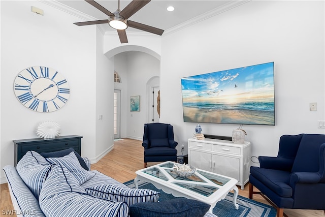 living room featuring a high ceiling, crown molding, ceiling fan, and light hardwood / wood-style flooring