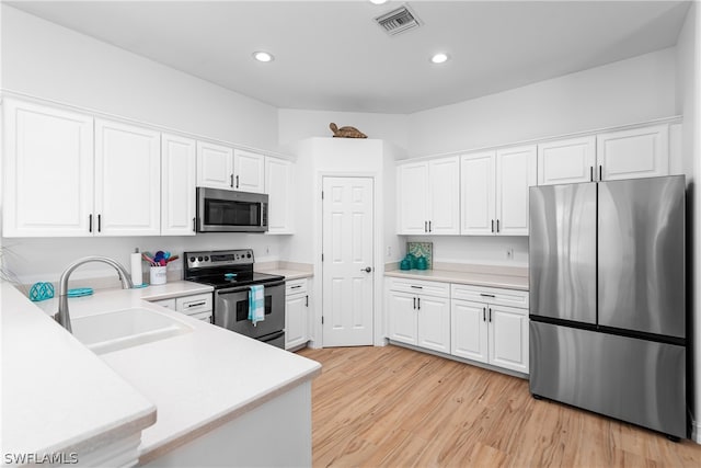 kitchen with sink, stainless steel appliances, light hardwood / wood-style floors, and white cabinets