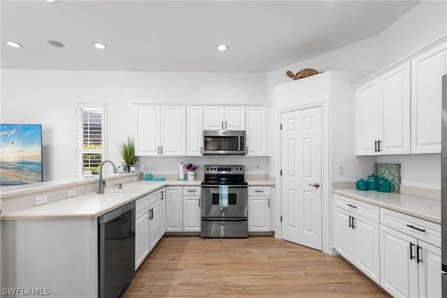 kitchen with appliances with stainless steel finishes, light hardwood / wood-style floors, sink, and white cabinets