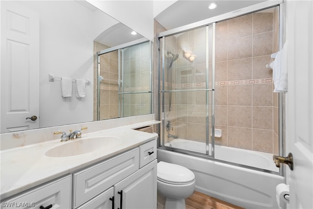 full bathroom with vanity, hardwood / wood-style flooring, enclosed tub / shower combo, and toilet