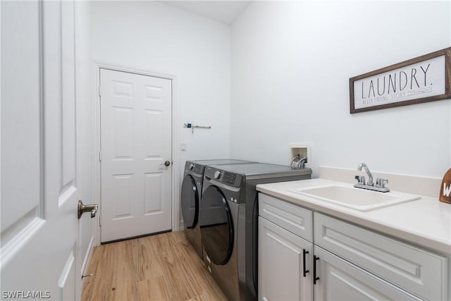 clothes washing area with cabinets, separate washer and dryer, sink, and light hardwood / wood-style floors