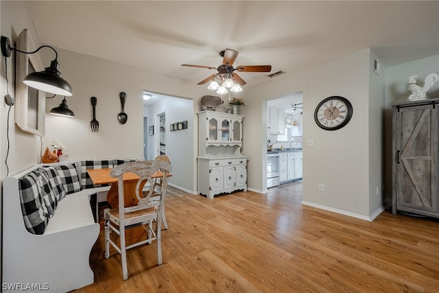 dining area featuring sink, ceiling fan, and light wood-type flooring