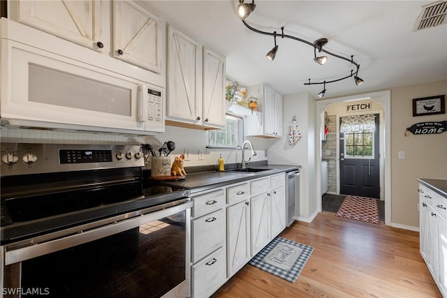 kitchen featuring white cabinets, light wood-type flooring, rail lighting, and appliances with stainless steel finishes