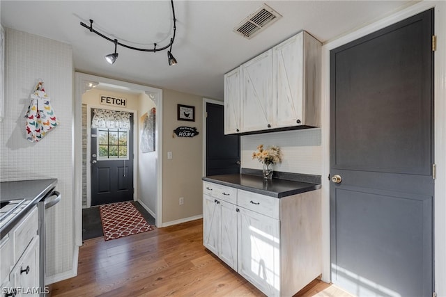 kitchen with white cabinets, dishwasher, track lighting, and light hardwood / wood-style flooring