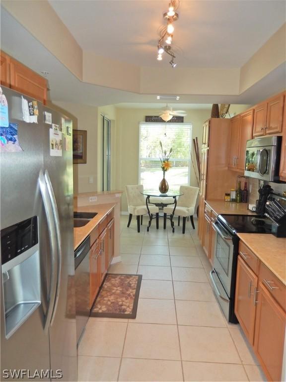 kitchen featuring a raised ceiling, appliances with stainless steel finishes, light tile patterned floors, and sink