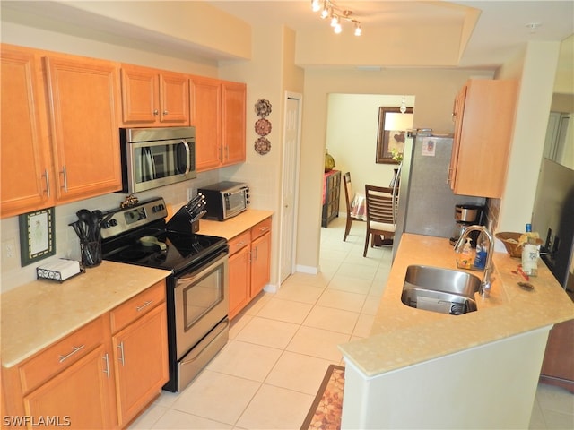 kitchen with sink, decorative backsplash, light tile patterned floors, and appliances with stainless steel finishes