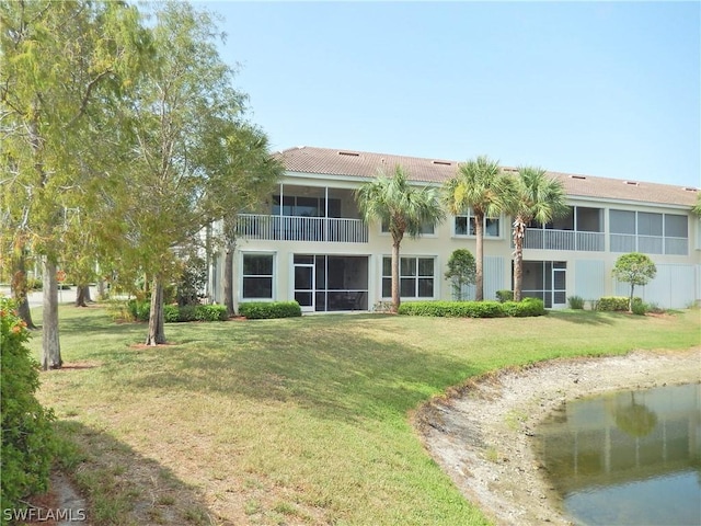 rear view of property featuring a sunroom and a lawn