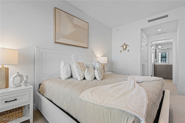 bedroom featuring connected bathroom and light colored carpet