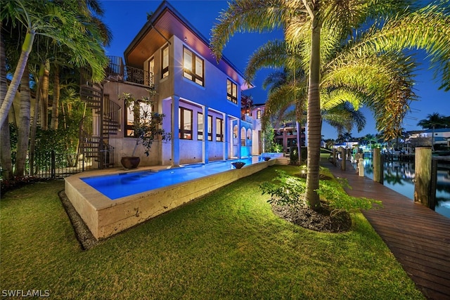 rear view of house featuring a yard, a water view, and a balcony