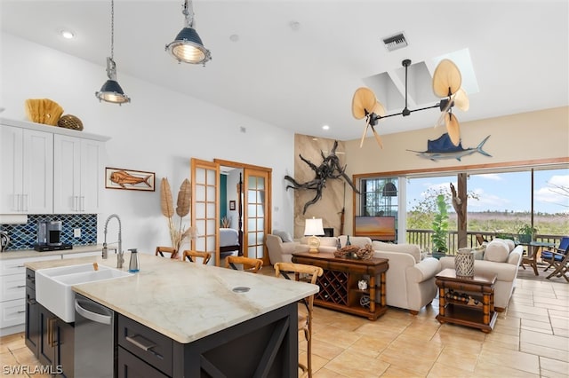 kitchen featuring white cabinetry, sink, an island with sink, and hanging light fixtures