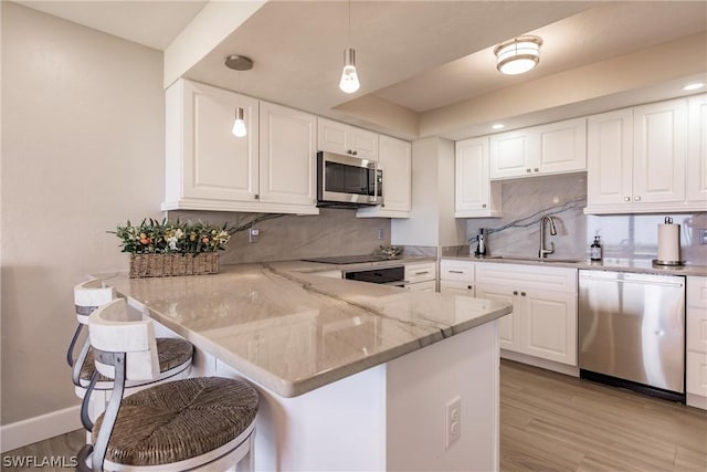 kitchen featuring sink, stainless steel appliances, kitchen peninsula, pendant lighting, and a breakfast bar area