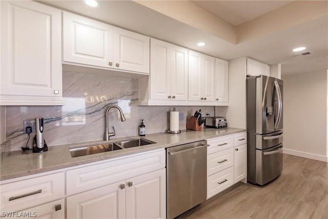 kitchen with sink, stainless steel appliances, backsplash, light hardwood / wood-style floors, and white cabinets