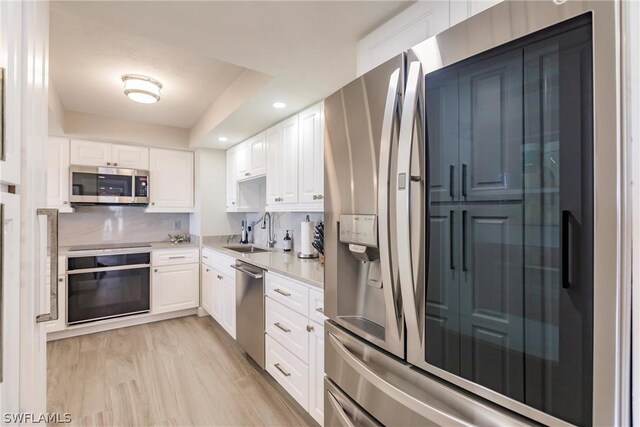 kitchen featuring sink, light hardwood / wood-style floors, white cabinetry, and black appliances