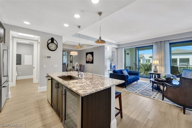 kitchen featuring sink, hanging light fixtures, stainless steel appliances, dark brown cabinetry, and light stone counters