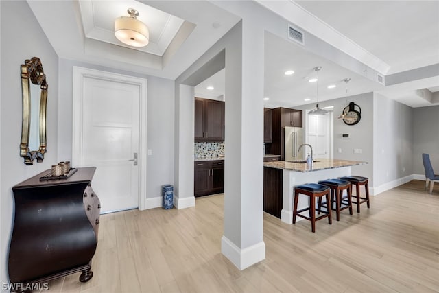 entryway featuring sink, ornamental molding, light hardwood / wood-style floors, and a raised ceiling