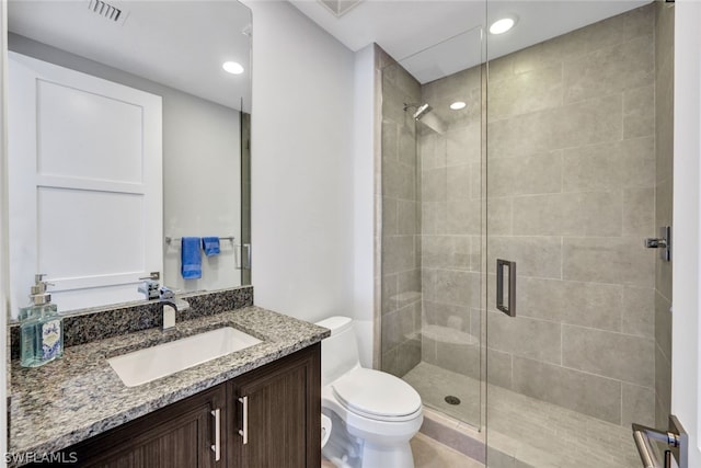 bathroom featuring toilet, vanity, and a shower with shower door