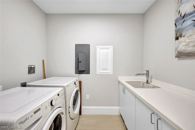 laundry area featuring light wood-type flooring, electric panel, sink, washer and dryer, and cabinets