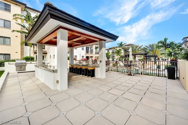 view of patio with area for grilling, an outdoor kitchen, a gazebo, and exterior bar