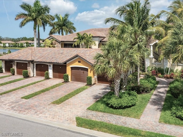 mediterranean / spanish-style home with stucco siding, decorative driveway, a garage, and a tiled roof