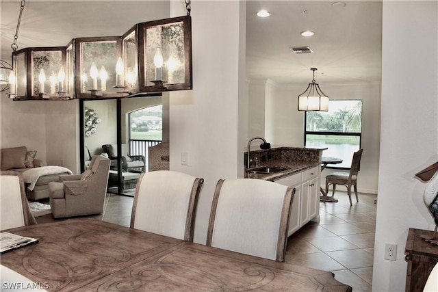 kitchen with light tile patterned floors, visible vents, a sink, white cabinetry, and decorative light fixtures