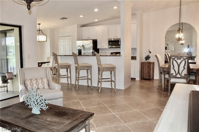 living area featuring arched walkways, light tile patterned floors, visible vents, and ornamental molding