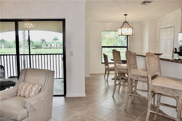 dining area with light tile patterned floors, visible vents, baseboards, and ornamental molding