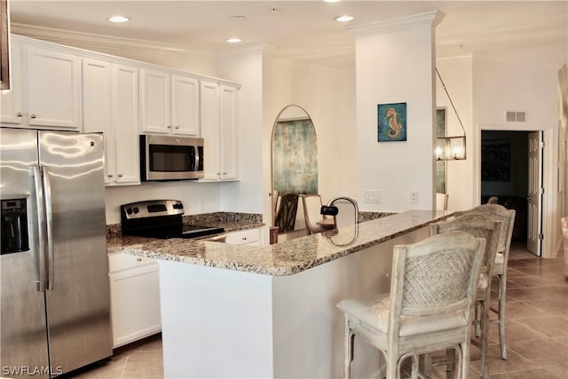 kitchen with visible vents, ornamental molding, stainless steel appliances, light tile patterned floors, and light stone countertops