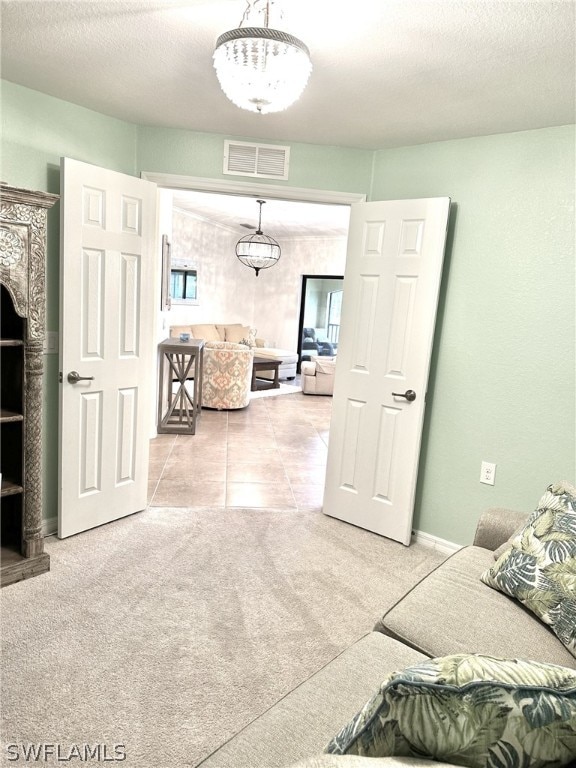 living area featuring a wealth of natural light, visible vents, light carpet, and a textured ceiling