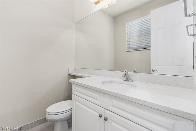 bathroom with toilet, large vanity, and tile floors