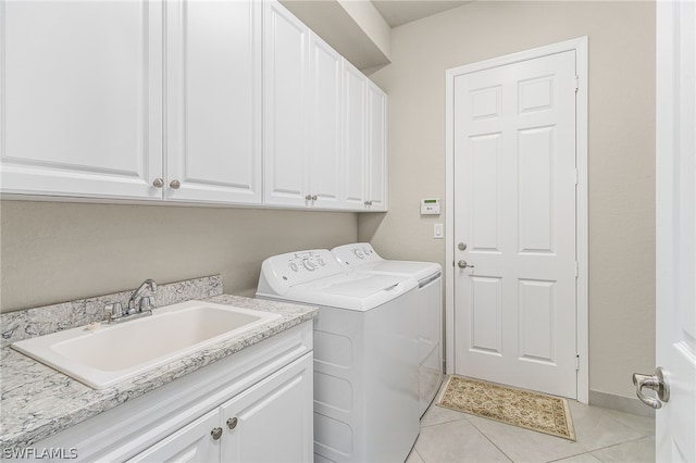 laundry room with light tile flooring, cabinets, separate washer and dryer, and sink