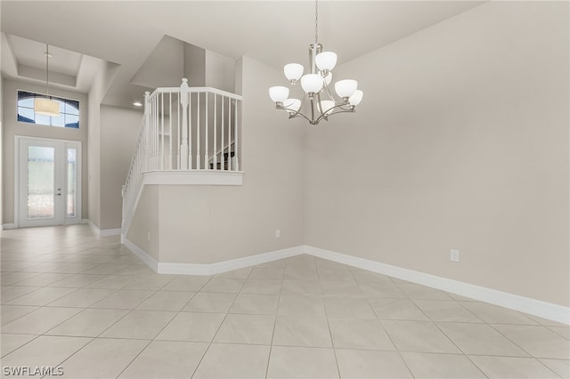 tiled empty room featuring a high ceiling and a notable chandelier