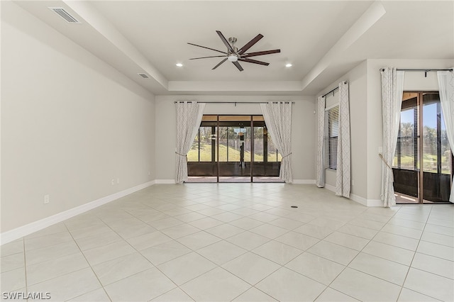 empty room with light tile floors, a raised ceiling, and ceiling fan